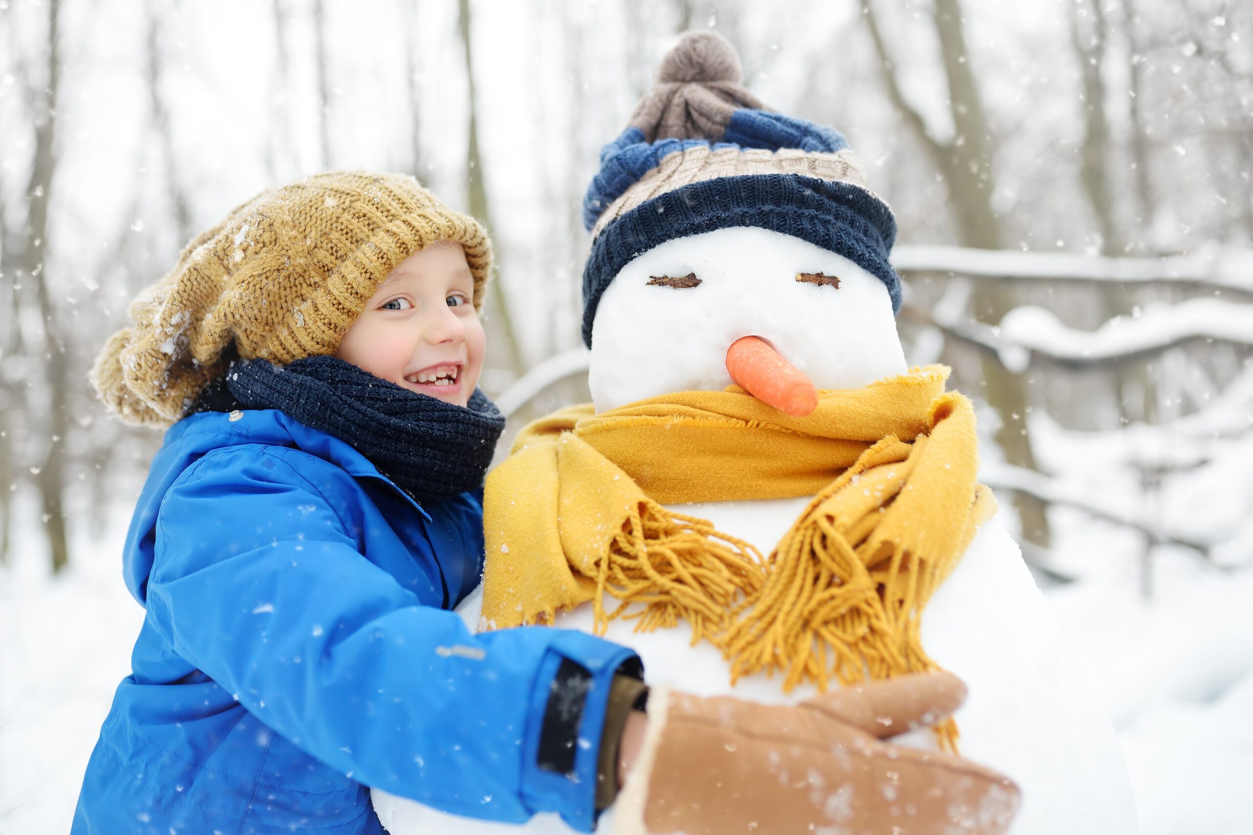 Little,Boy,Building,Snowman,In,Snowy,Park.,Child,Embracing,Snowman